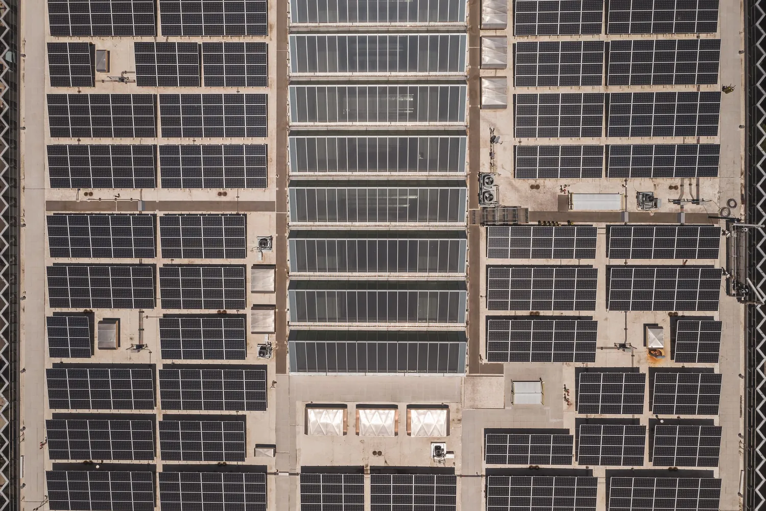 Luftaufnahme eines Hallendachs, dicht mit Solarmodulen belegt, dazwischen Lichtbänder und Lüftungsgeräte